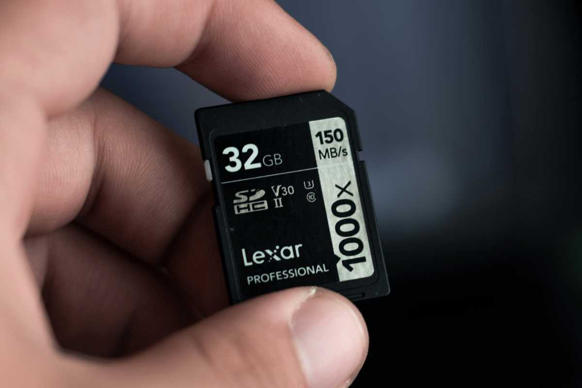 Man holding up 32GB Lexar SD card between fingers