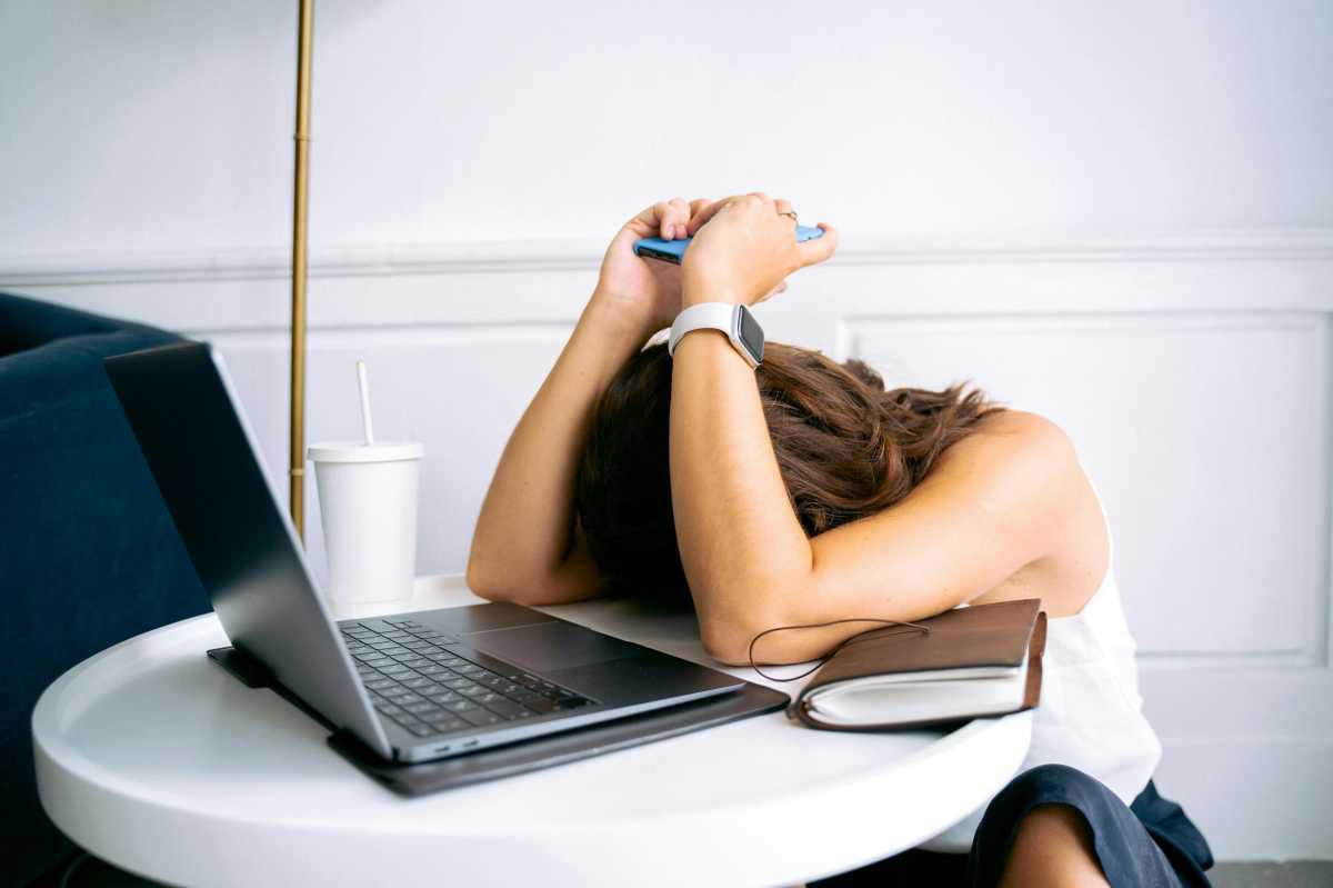 frustrated woman holding phone with laptop