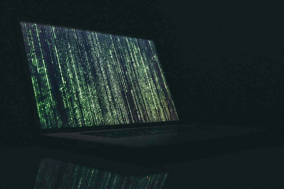 Laptop in darkness with matrix-style green hacking on screen