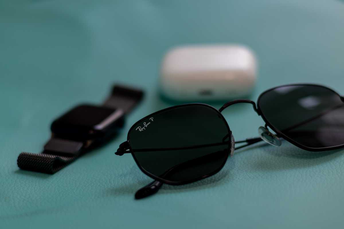 Ray Ban shades next to Apple Watch and AirPods case