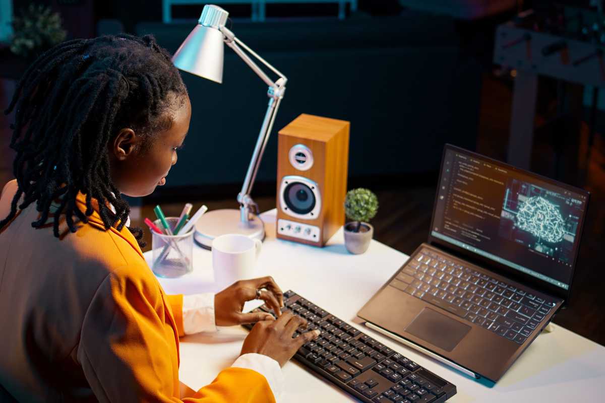 Woman using keyboard with laptop propped up on desk in home office