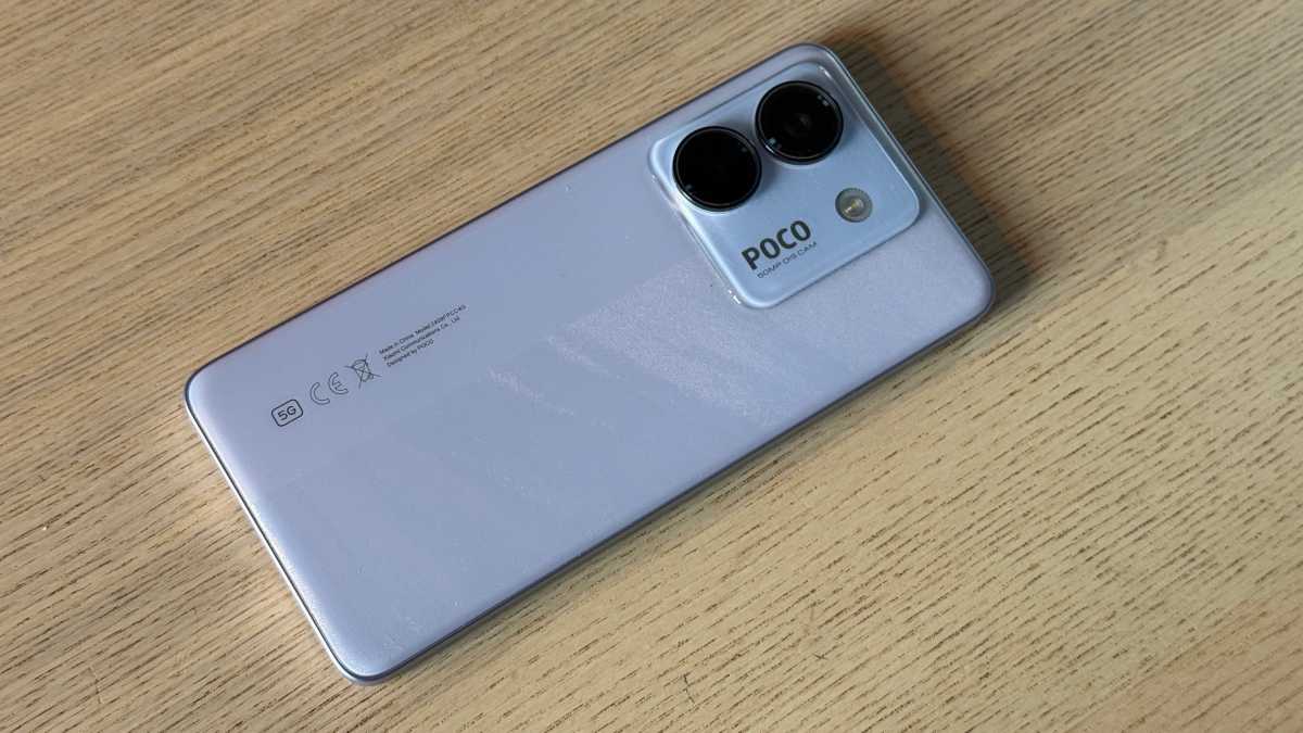 A photo of the Poco M7 Pro against a neutral backrground on a wooden table.