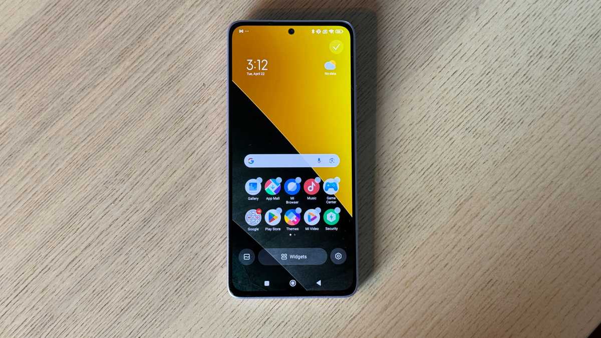 A photo of the Poco M7 Pro against a neutral backrground on a wooden table.