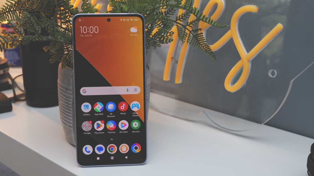 A photo of the Poco M7 Pro against a neutral backrground on a wooden shelf