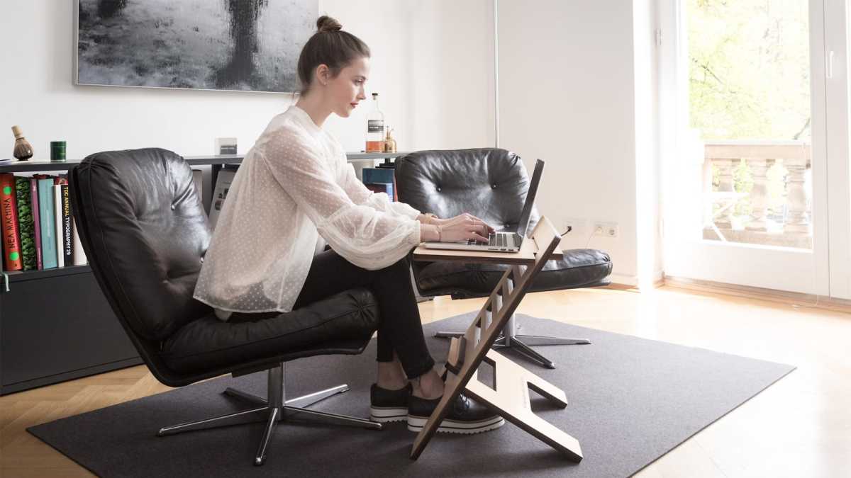 Woman sitting with laptop on a small desk with poor posture