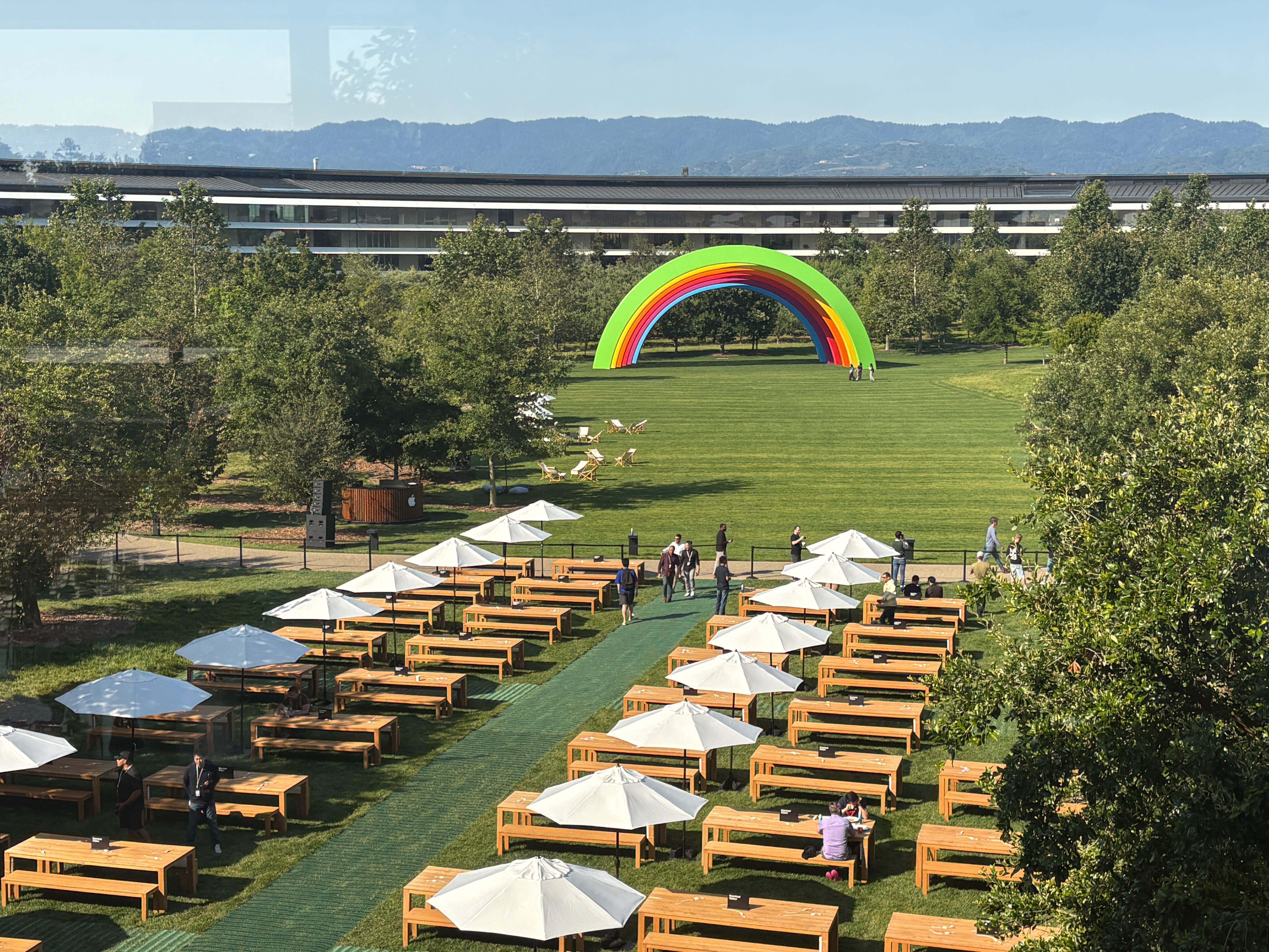 Apple Park tables on a field with the rainbow sculpture in the background