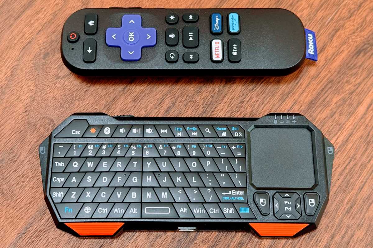 A Roku remote and a mini keyboard remote with trackpad, nearly the same size but the keyboard remote is a little taller.