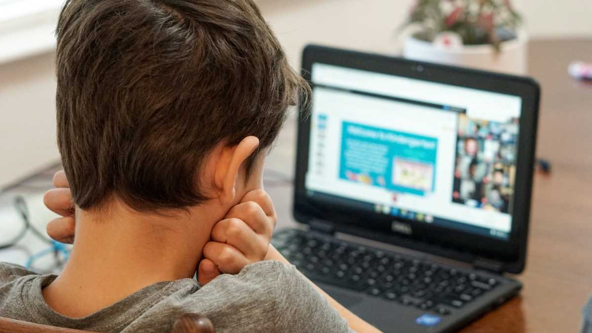 Kid student boy not happy using a Chromebook laptop for school
