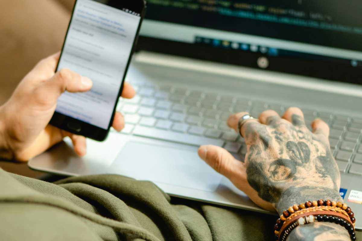 Man at a laptop with a phone in his hand