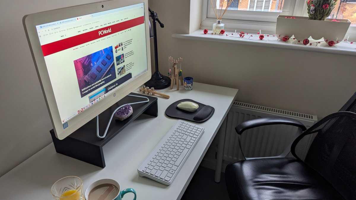 Coffee next to computer at home office desk with PCWorld on monitor