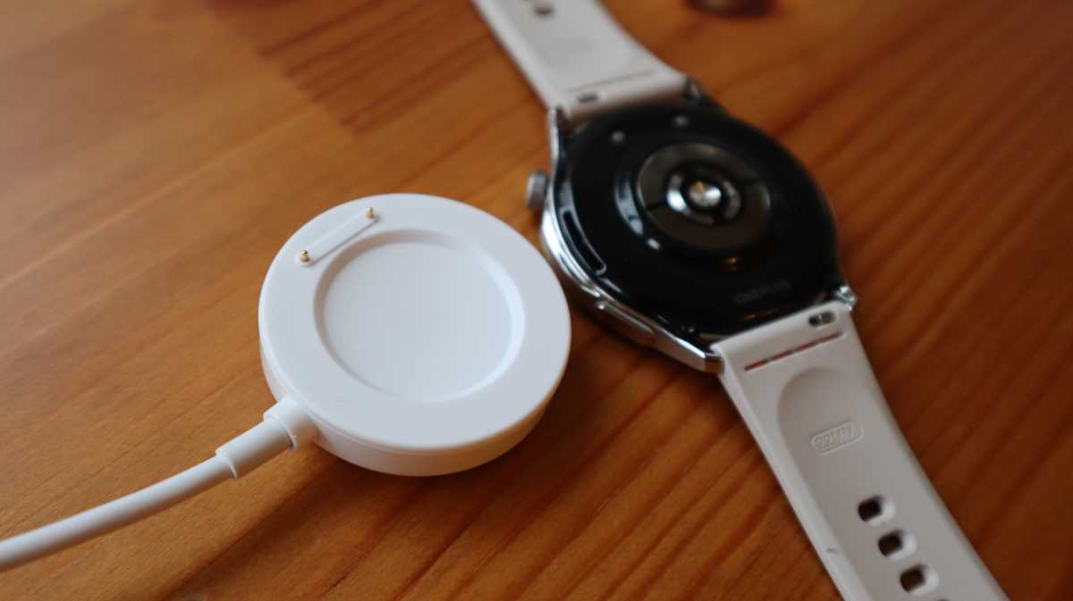 The OnePlus Watch Lite next to its charger