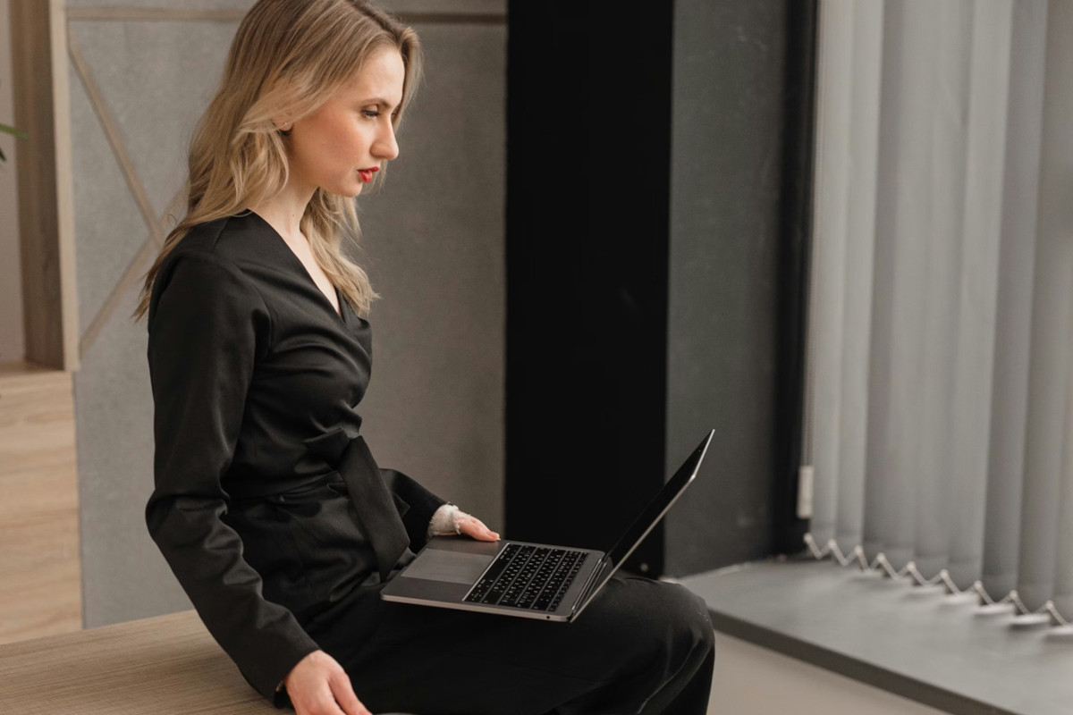 Woman sitting with laptop on her lap and neck craned down