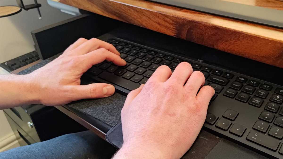 Hands on keyboard tray sitting below desk height