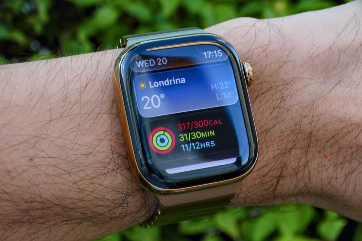 Apple Watch in gold aluminum on a wrist with widgets showing