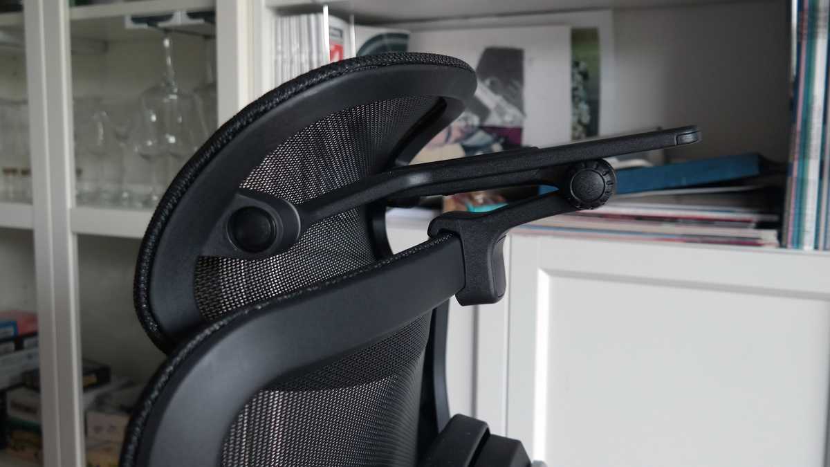 Schwarze gepolsterte Kopfstütze an einem Bürostuhl vor weißen Schranktüren.