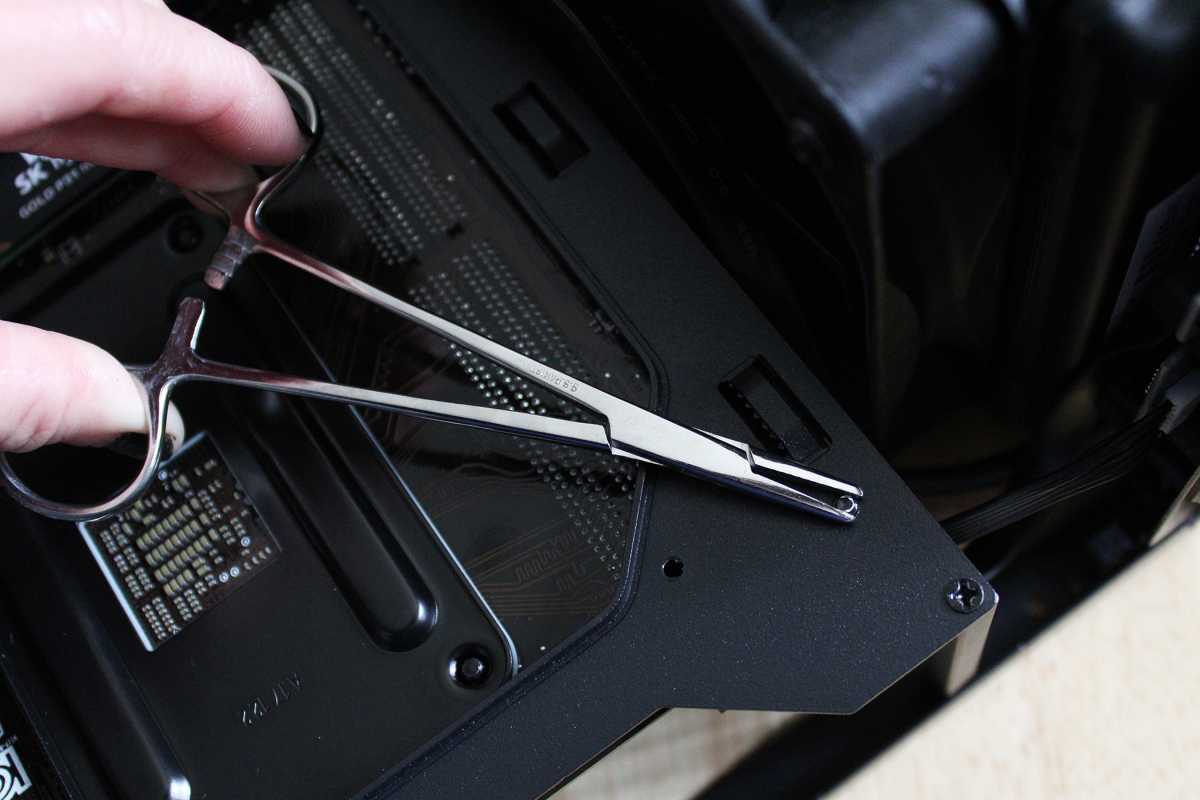 Hemostat clamped to the back of a motherboard standoff screw